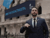 a man in a suit and tie stands in front of a sign that says " look for our active etfs "