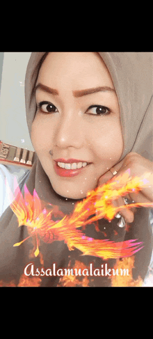 a woman wearing a hijab is smiling with a picture of a phoenix behind her and the words assalamualaikum on the bottom