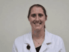 a woman in a lab coat is smiling for the camera .