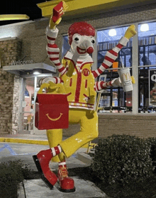 a statue of mcdonald 's ronald mcdonald holding a box of happy meals and french fries