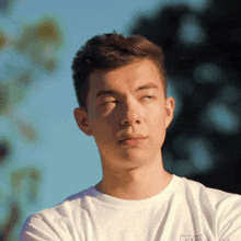 a young man wearing a white t-shirt with a logo on the back that says ' california ' on it