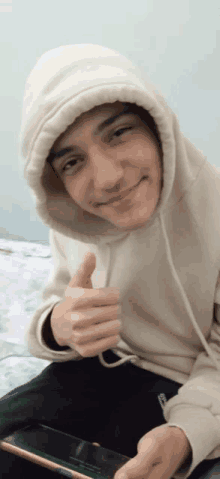 a young man wearing a hoodie giving a thumbs up