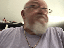 a man with glasses and a beard is wearing a necklace