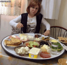 a woman sits at a table with a tray of food and a box of becel on it