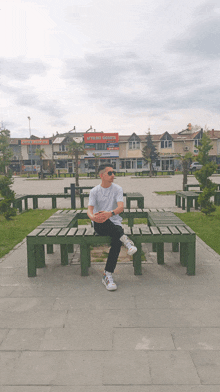 a man sits on a wooden bench in front of a store called ataköy sebze