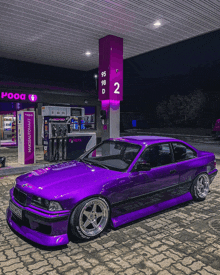 a purple car is parked in front of a pooa gas pump