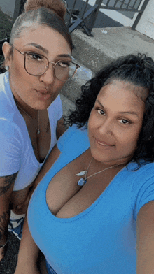 two women are posing for a picture with one wearing a blue shirt