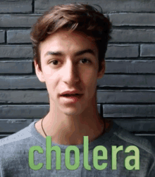 a young man wearing a grey sweater with cholera written on it