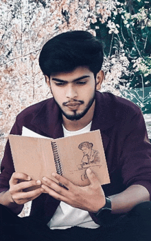 a young man is reading a book with a drawing of a man on the cover