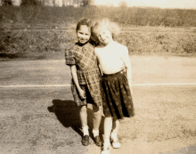 a black and white photo of two young girls standing next to each other