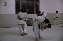 a group of men are practicing judo in a room with a sign on the wall that says ' a ' on it