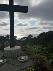 a large black cross with a view of the ocean behind it