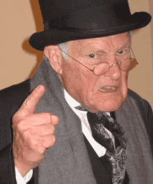 an old man wearing a top hat and glasses is pointing