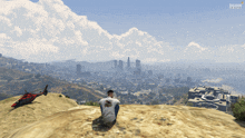 a man sitting on top of a hill with a helicopter in the background