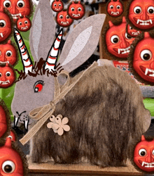 a stuffed animal with horns and a flower around its neck is surrounded by devil faces