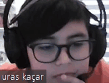 a young boy wearing glasses and headphones with the name uras kacar on the bottom right