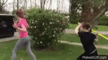 a woman in a pink shirt is standing next to another woman in a black shirt in a park .