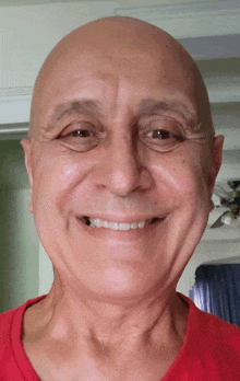 a bald man wearing a red shirt is smiling