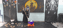 a woman in a witch costume is standing in front of a halloween decoration