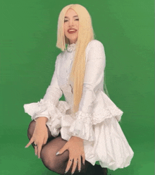 a woman wearing a white dress and black tights is kneeling down