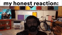 a man with a beard is wearing headphones in a room with a sign that says my honest reaction .