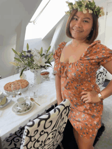 a woman with a flower crown on her head stands in front of a table