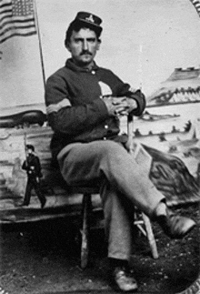 a man in a military uniform sits on a stool