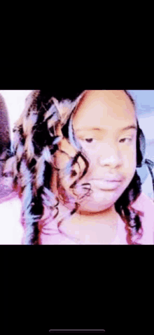 a young girl with curly hair is looking at the camera with a serious look on her face .