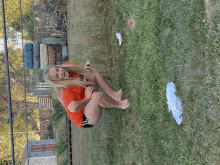 a woman in a red shirt is squatting in the grass