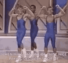 a group of men in blue jumpsuits are dancing together .