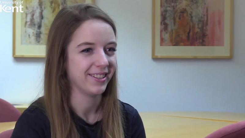 Rebecca Wood, long fair hair, dark jumper sitting down