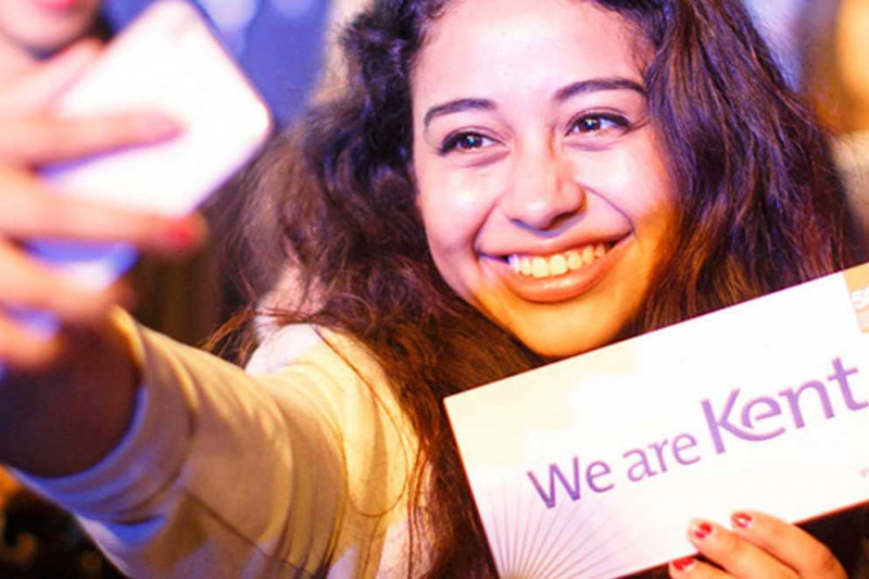 Female student taking selfie with We are Kent sign