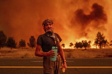Grant Douglas pauses to drink water while evacuating as the Park Fire jumps Highway 36 near Paynes Creek in Tehama County, Calif., Friday, July 26, 2024. 
