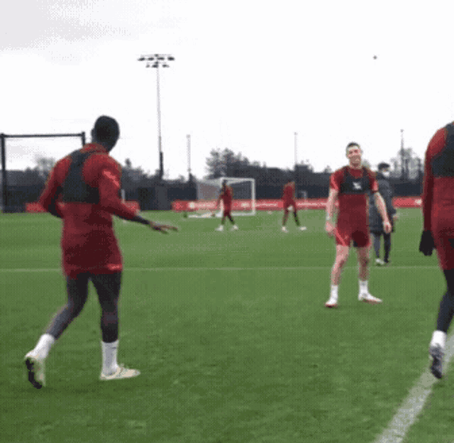 a group of soccer players are playing on a field and one of them is wearing a jersey that says ' liverpool '