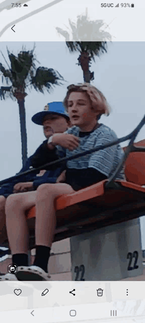 a phone screen shows a picture of two boys on a roller coaster