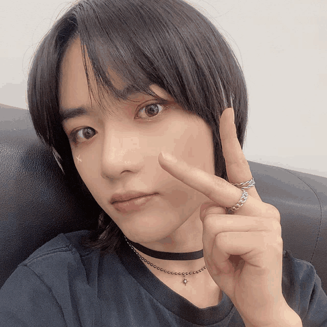 a person wearing a choker and a ring giving a peace sign