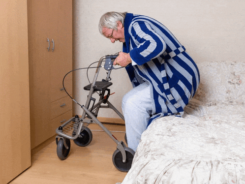 an elderly man in a blue and white robe is sitting on a bed with a walker