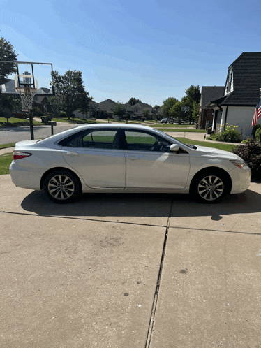 a white car is parked in front of a basketball hoop in a driveway