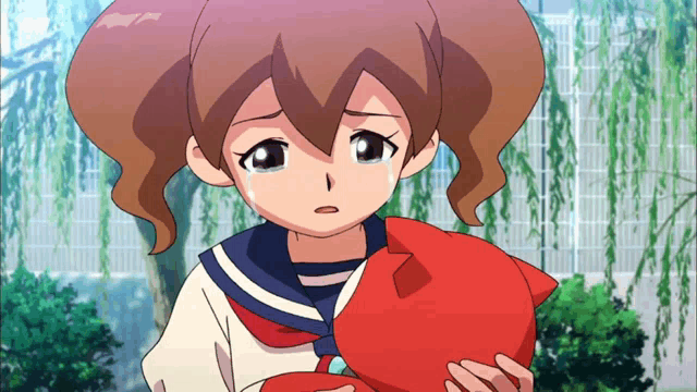 a girl in a school uniform is crying while holding a red cat