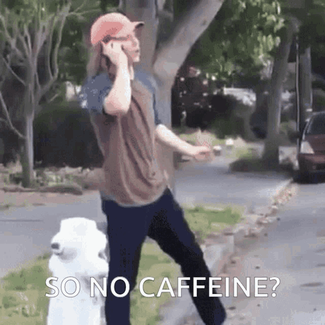 a man talking on a cell phone while standing next to a white dog with the words so no caffeine written below him