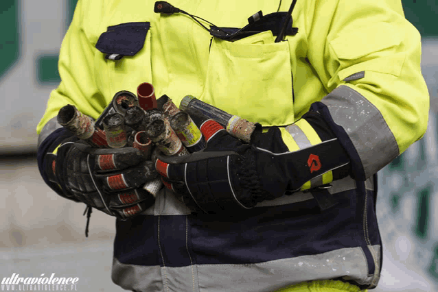 a man in a yellow jacket is holding a bunch of canisters