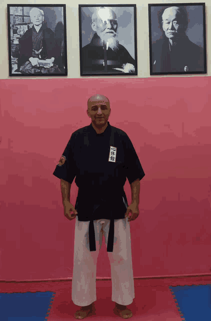 a man in a karate uniform stands in front of framed pictures