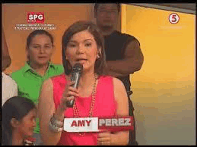 a woman in a pink shirt is holding a microphone and a sign that says amy perez