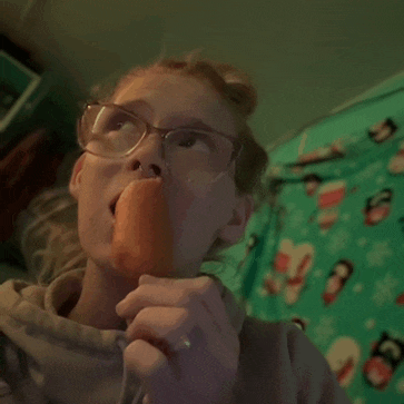 a girl with glasses is eating an orange