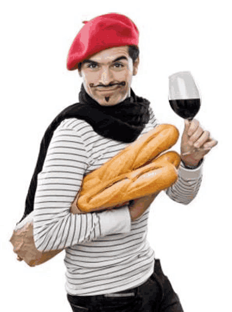 a man wearing a red beret is holding a stack of bread and a glass of wine .