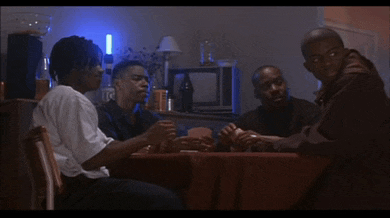 a group of men sit around a table with cards