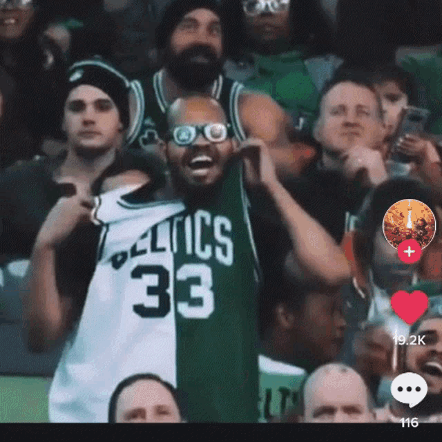 a man wearing a celtics 33 jersey stands in a crowd of people