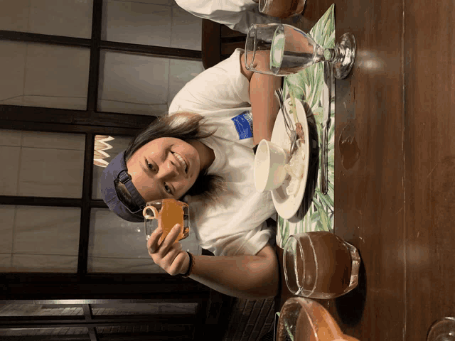 a woman sits at a table with a cup of orange juice and a glass of water