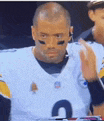 a football player wearing a white jersey with the number 4 on it is sitting on the sidelines .