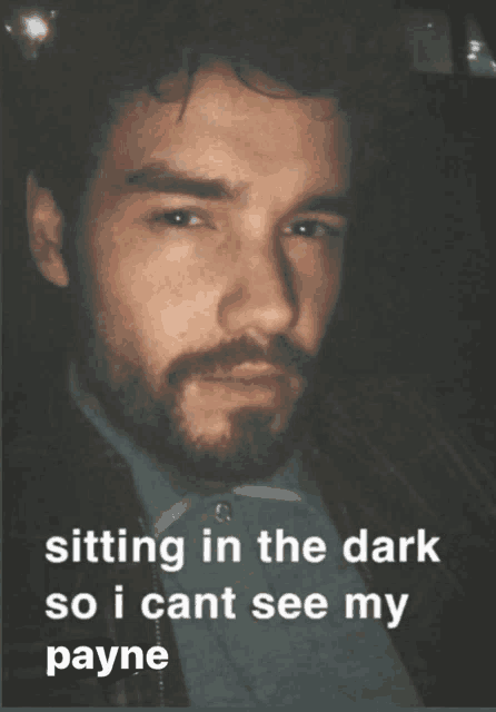 a man with a beard is sitting in the dark so i can t see my payne